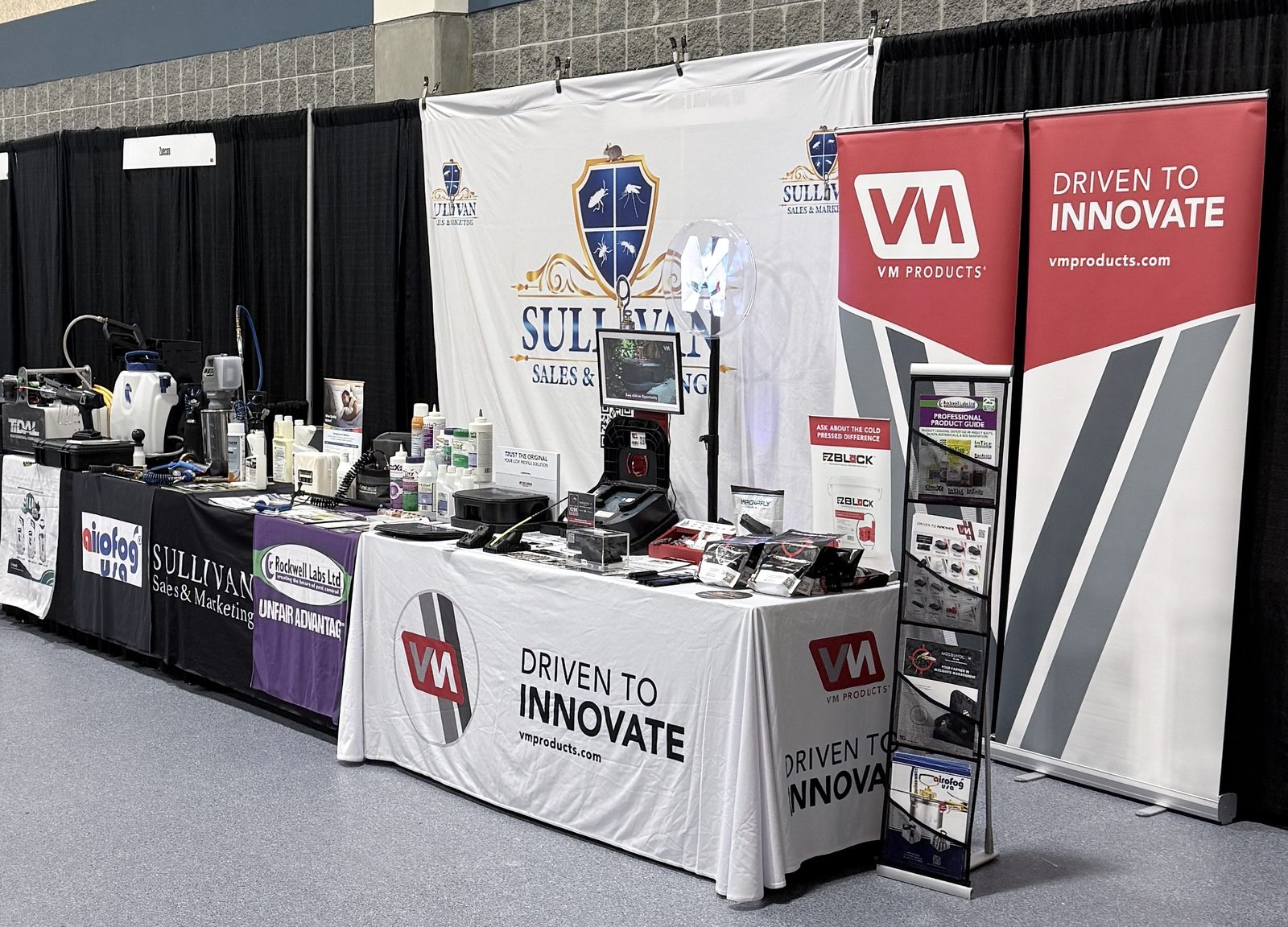 The Sullivan Sales and Marketing exhibit at a pest-management conference, with equipment, bait stations, and manufacturer literature laid out for attendees